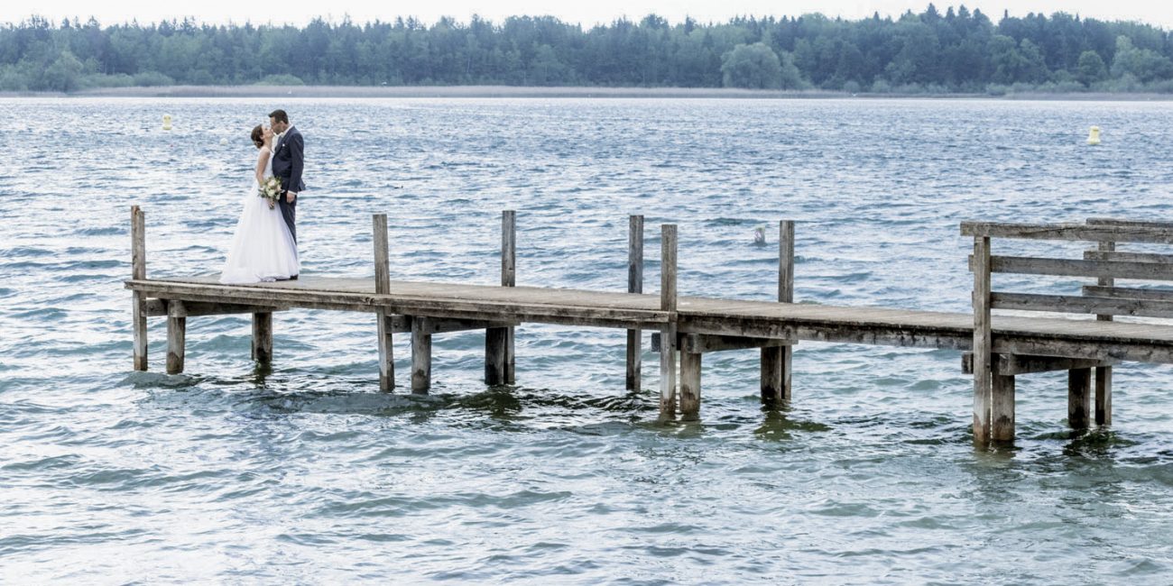 hochzeitspaar steht auf einem steg am chiemsee