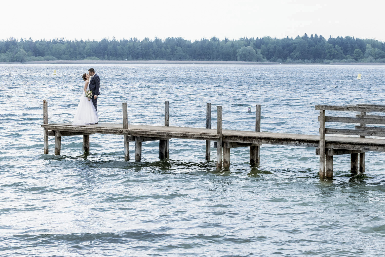 hochzeitspaar steht auf einem steg am chiemsee