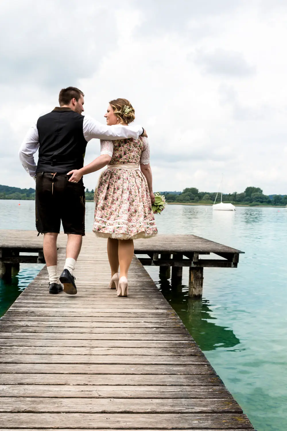 Ein Hochzeits Paar geht über einen Stega am Ammersee