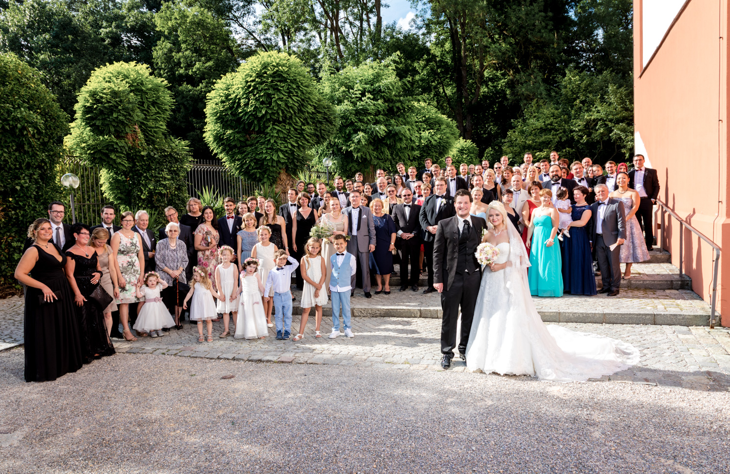 Gruppenbild einer Hochzeitsgesellschaft vor einer Kirche, die Hochzeitsfotografie mit großen Gruppen zeigt